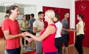 Group of adult spanish people dancing salsa in studio