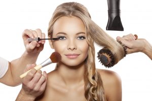 Professional makeup artist and hairdresser are preparing a fashion model. Portrait of beautiful blonde girl with blue eyes. Isolated on white background